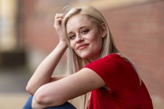 A beautiful blonde woman poses joyfully for the camera, showcasing her stylish spring clothing.