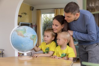 A family is sitting at a Globus and planning a trip on holiday to Austria