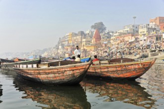 Varanasi, Uttar Pradesh, India, Asia, Two boats floating side by side on a river with urban scenery
