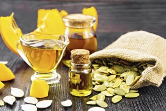 Pumpkin oil in vial, gravy boat and a jar, seeds in a bag and on table, slices of vegetable on