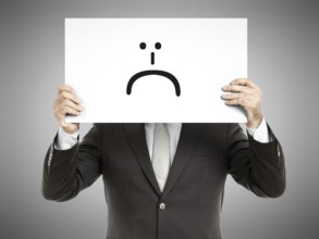 A business man holding a paper in front of his face with a smiley sign on it