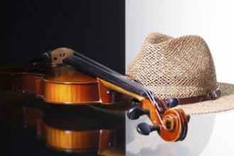 Old violin and straw hat isolated on black and white background and glass desk