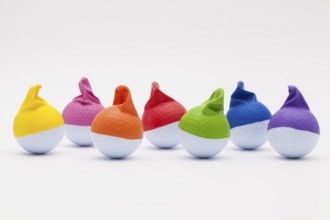 White golf balls with funny caps on the white background. Funny golf concept