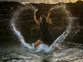 Middle-aged woman dancing and throwing water in the air, Maioris beach, llucmajor, Majorca,