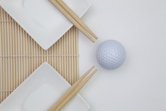 Top View Of White Empty Sushi Plates With Bamboo Chopsticks and Golf Ball. Golf Design