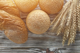Long loaf bread wheat ears on wooden surface