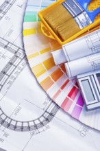 Rolled blueprints and paint brushes in tray calculator on color palette