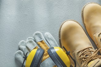 Safety lace boots protective gloves earmuffs on concrete background