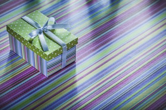 Cardboard present box with ribbon on striped tablecloth celebrations concept