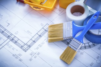 Blueprint with paint roller tray brushes bottle duct tape and wooden meter copy space image