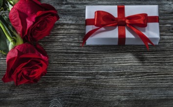 White gift boxes red roses on wooden board