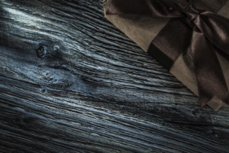 Wrapped brown gift box on wooden board
