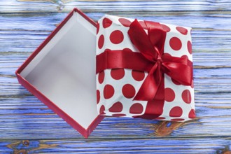 Opened gift box with bow on vintage wooden board