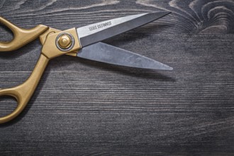 Pair of golden scissors on vintage wooden board top view