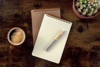 Notebook with a pen, coffee, and plant, overhead flat lay shot on a rustic wooden desk, a mockup,