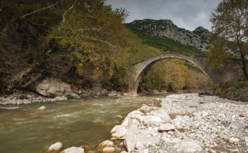 Ancient, stoned, arched bridge St. Vissarion on the Portaikos river in autumn. Trikalla pyli