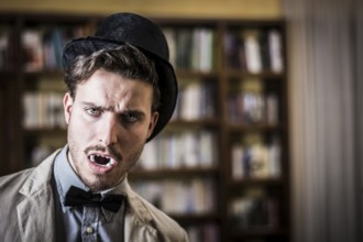 Close up Young Handsome White Vampire with Black Top Hat Inside the Mini Library