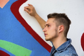 Attractive young blond man against colorful graffiti wall, wearing denim shirt