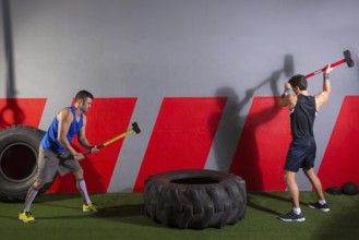 Sledgehammer Tire Hits men workout at gym with hammer and tractor tire