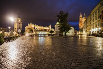 Poland, Krakow, Main Square in Old Town after the rain, city skyline at night with Town Hall Tower,