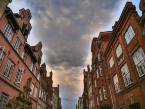 Historic red brick buildings under a dramatic cloudy sky, gothmund, travemünde, lübeck, germany