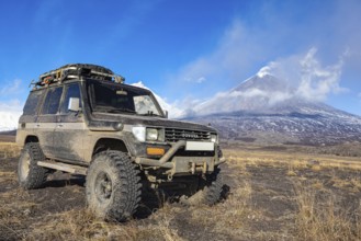 Lifted sport utility vehicle Toyota Land Cruiser Prado on background eruption active Klyuchevskoy