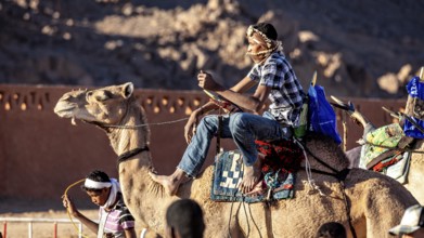 Man riding a camel through the desert, surrounded by mountains, Tuareg camel rider at the