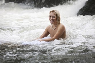 Young naked woman swimming in a river
