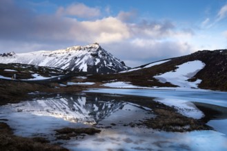 Icelandic landscape with frozen lake and stapafell mountains covered in snow and reflected on water