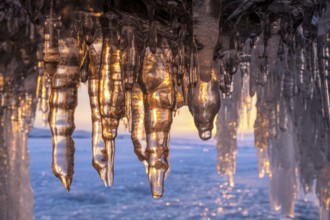 Ice cave on Baikal lake in winter. Blue ice and icicles in grotto in the sunset sunlight. Olkhon