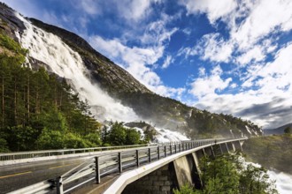 Huge powerful and roaring cascading Langfossen waterfall on the Vaule river. The bridge is fenced