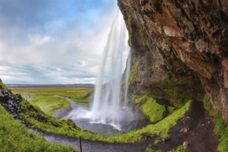 Seljalandsfoss waterfall in July. Passage under the waterfall. Sunny day in Iceland. Photo taken