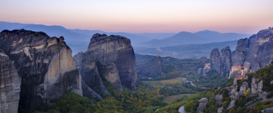 Panoramic view of majestic rock formations and a valley with a monastery at dusk, Meteora valley