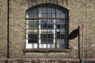A no stopping sign casts a shadow on the brick wall on the disused industrial site of an old