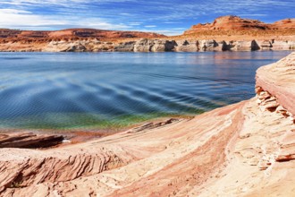 The smooth emerald water of the lake contrasts with the bright red terracotta sandstone shores.