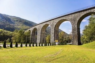Picturesque Julian Alps. Beautiful sunny autumn day. Majestic powerful bridge over the river Idrija