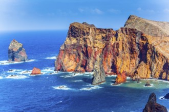 The west coast of the island of Madeira - red rocks, turquoise surf. The blinding midday sun