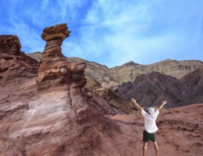 Unique outcrops in the mountains of pink sandstone. A lone tourist threw his hands up in delight in