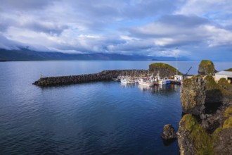 White fishing boat in the harbor pier fishing village Arnastapi. Sunset on the sea fjord in Iceland