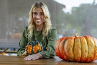 A stunning blonde model poses in a vibrant pumpkin field, wearing a stylish autumn outfit with a