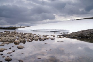 Heavily clouded sky reflecting in a lake on the Norwegian mountain plateau Aurlandsfjellet