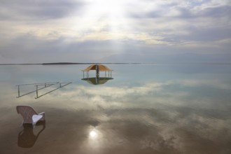 Medical beach on the Dead Sea, Israel. Round gazebo and a beach chair in the water. Cloudy sky