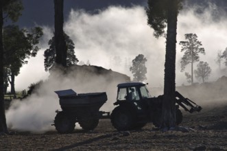 Tractor spreading lime with a fertiliser spreader, West Coast, New Zealand, Oceania