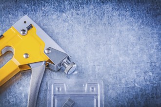 Set of stapler gun chrome staples on scratched metallic background