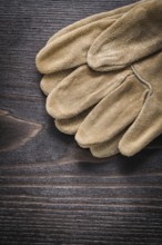 Pair of leather working gloves on vintage wooden board close up view construction concept