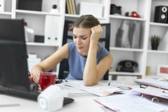 Beautiful young girl in a blue dress is working in the office. photo with depth of field
