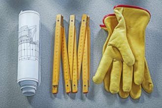 Leather protective gloves construction plans wooden meter on concrete background building concept