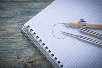 Vintage drawing compass pencil checked copybook on wood board construction concept