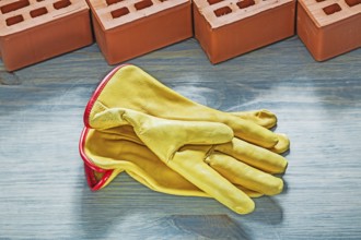 Orange bricks yellow safety gloves on wooden board bricklaying concept