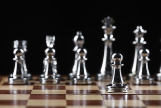 Steel chess figures standing on wooden chessboard. Intellectual duel and tactical battle in